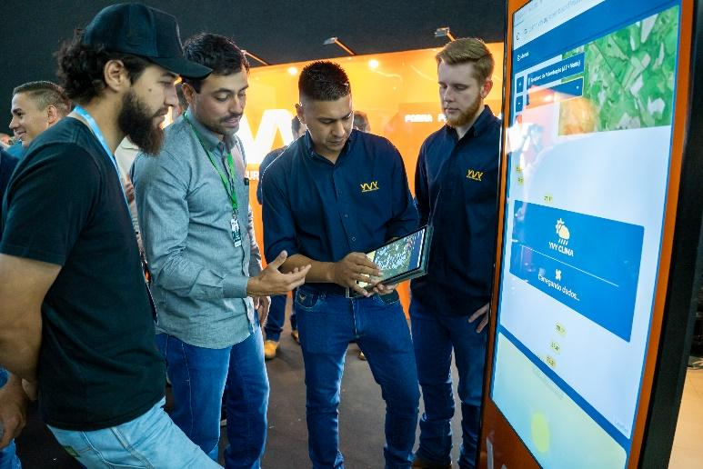 Asistentes interactuando con soluciones agrotech en un stand del Simposio de Maíz.